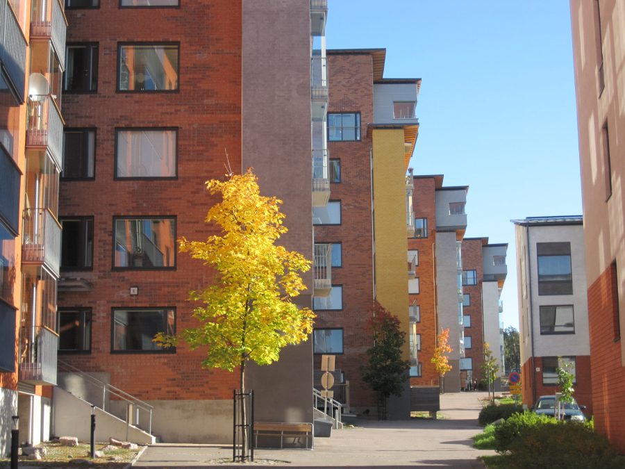 Sunny view of multiple apartment buildings with trees in front