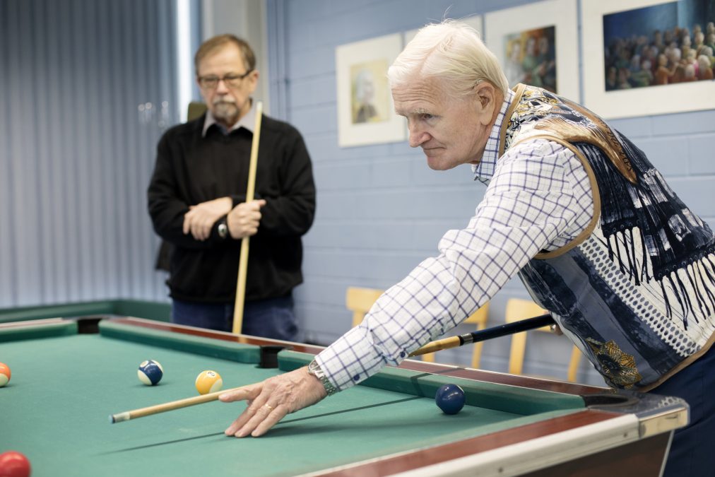 Two older people playing billiards